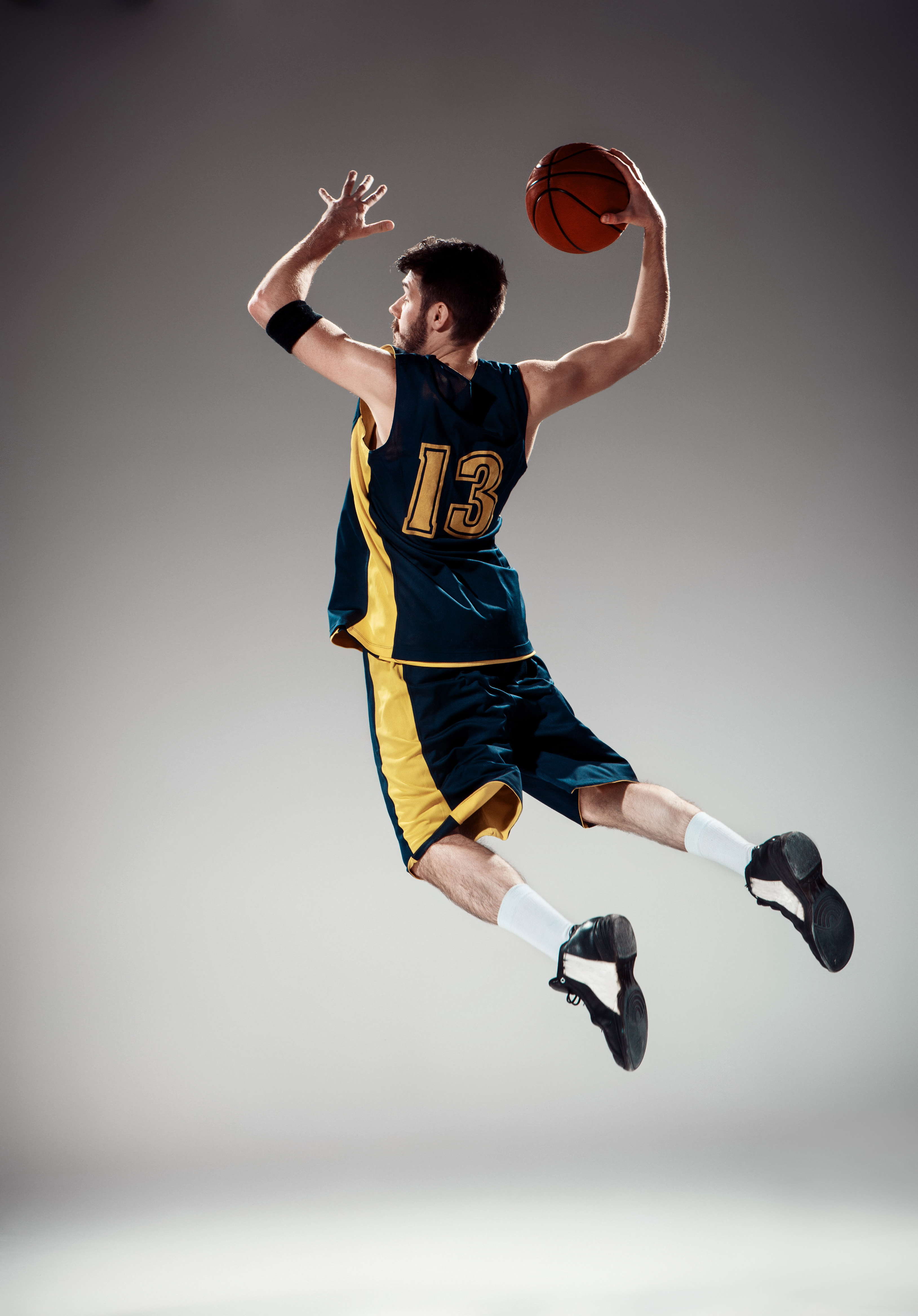 Full length portrait of a basketball player with a ball against gray studio background